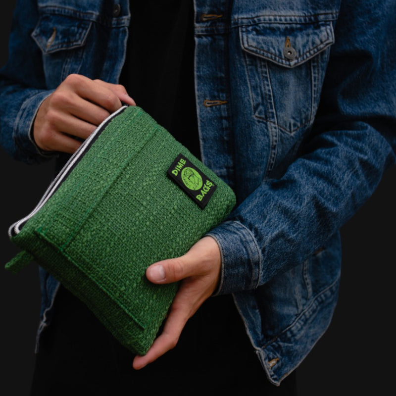 710 Pipes Smoke Shop green Dime Bags padded hempster pouch held by a person wearing a denim jacket