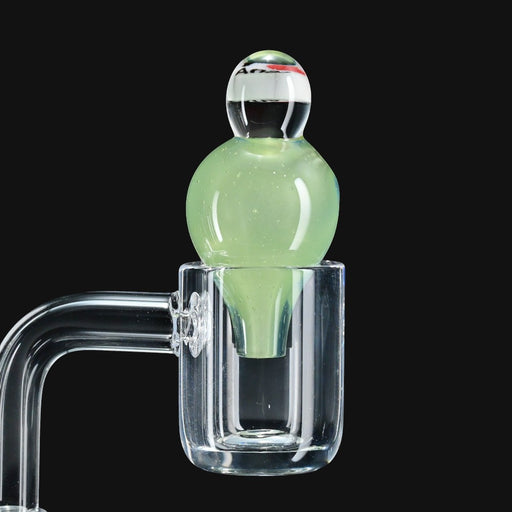 710 Pipes Smoke Shop JuneBug Profane bubble cap in light green glass sitting in a clear quartz banger