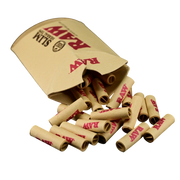 710 Pipes Smoke Shop RAW Slim herbal rolling tips spilling out of their tan paper packaging on a black background.