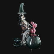 710 Pipes Smoke Shop Rich Villa "Witches Get Stoned" glass recycler rig with witch figure stirring cauldron, pink accents, and witch hat.