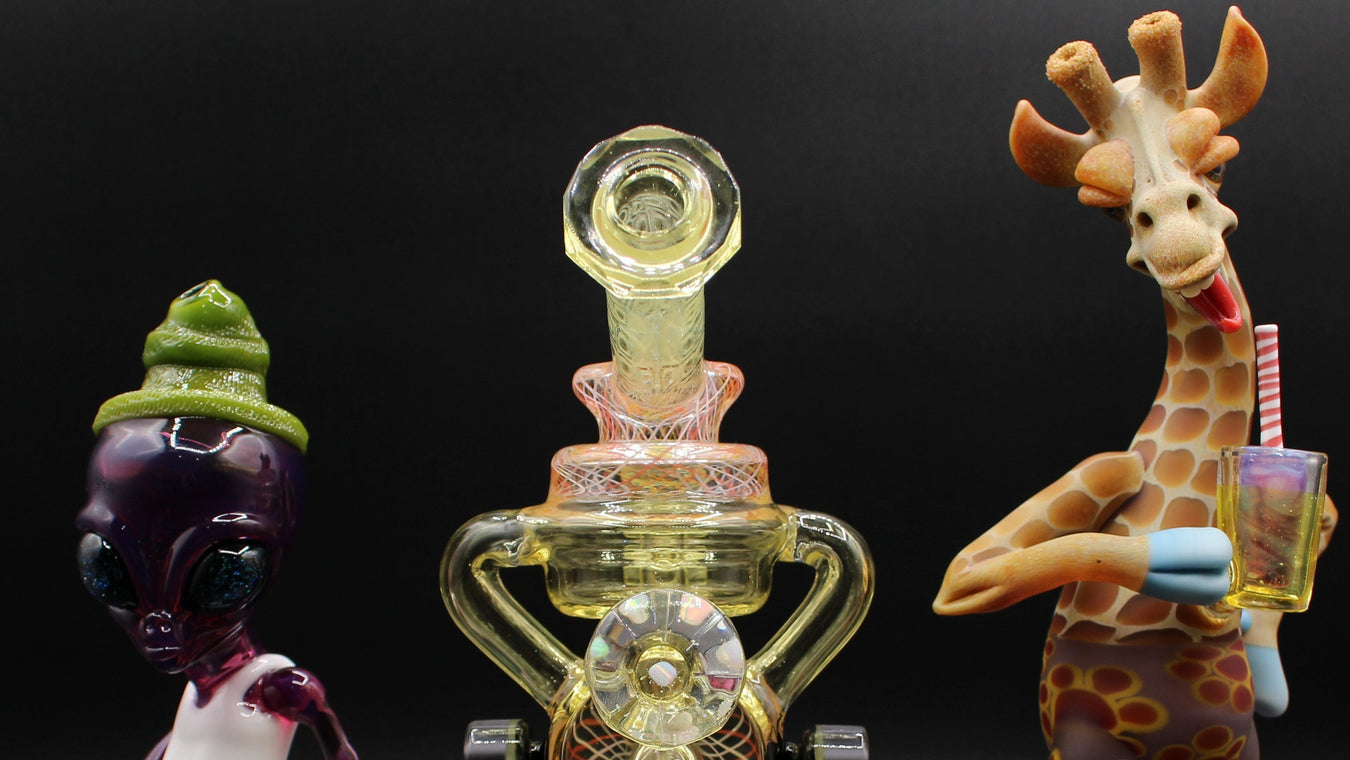 Three glass sculptures of an alien, a transparent figure, and a giraffe with a book on a black background.