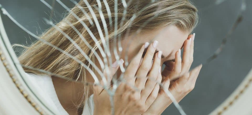 Person with hands over their face in a distressed double-exposure image