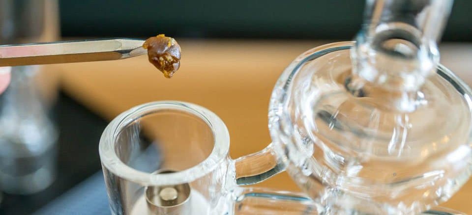 Metal Dabbing Tool Placing Wax Concentrate Into Glass Dab Rig