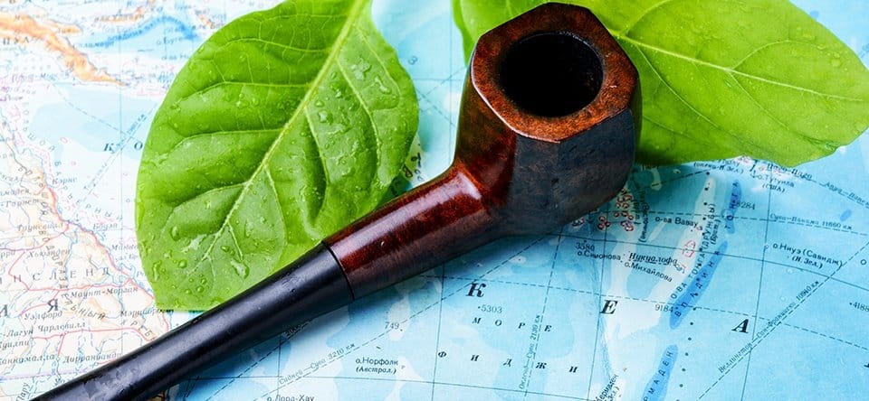 Tobacco pipe with green leaves resting on a map
