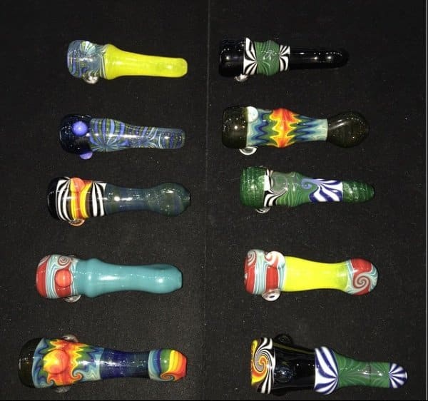 Assortment of colorful glass chillum pipes displayed in a case