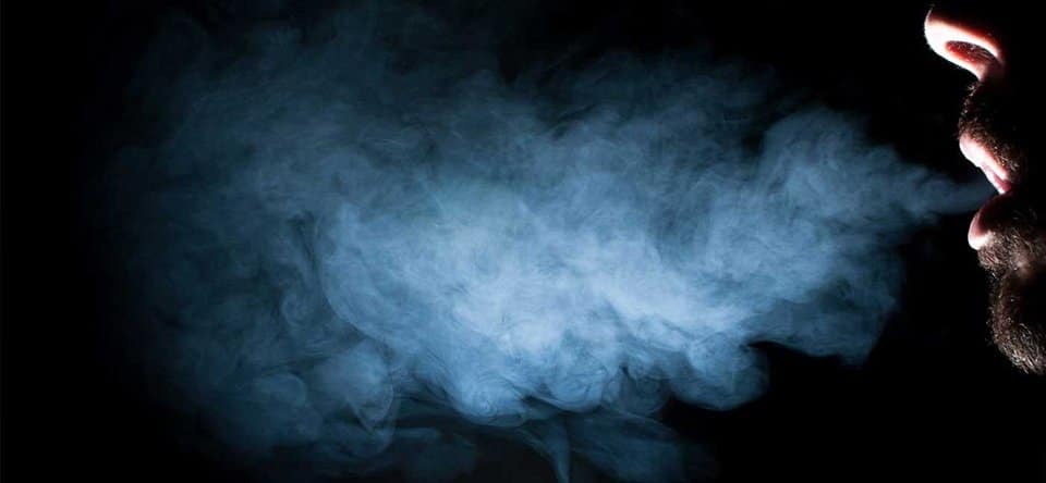 Silhouette of a man exhaling a cloud of smoke