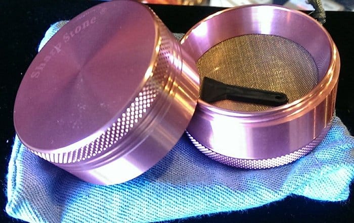 Pink metal herb grinder opened to show the screen
