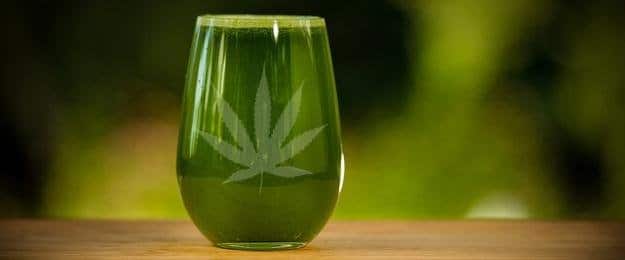 Green glass with a cannabis leaf design filled with green juice