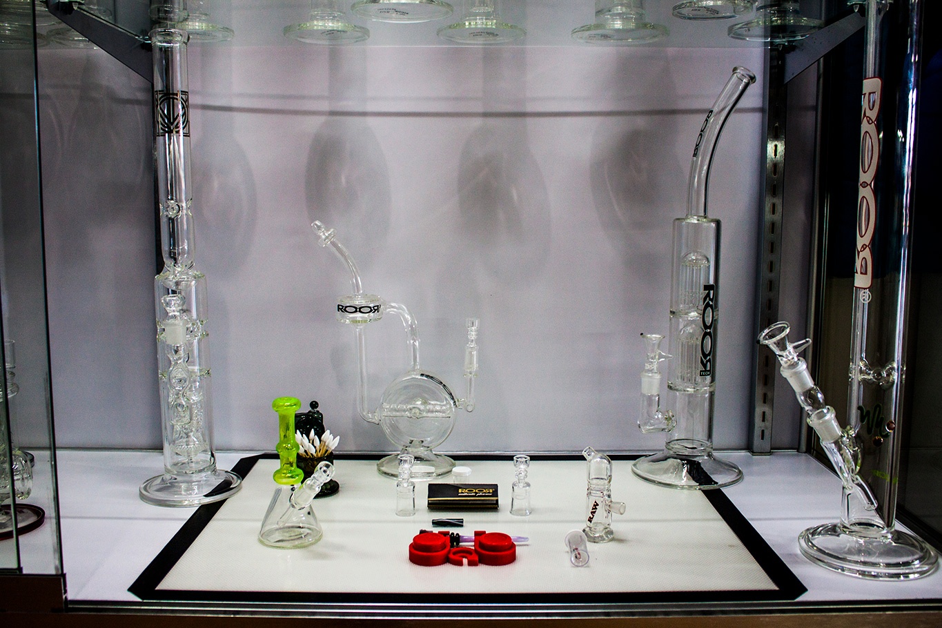 Assorted sizes of percolater bongs by ROOR in glass display case