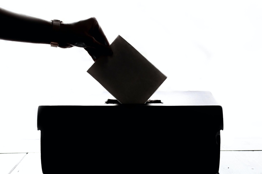 Hand placing finished ballot into Montana ballot box