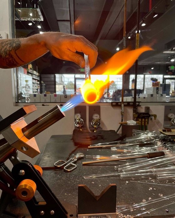 Glassblower creating heady glass bong with torch at Northglenn smoke shop
