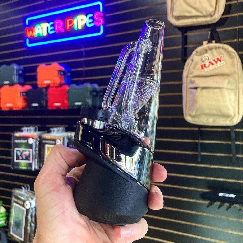 Puffco Peak smart dab rig in hand at 710 Pipes smoke shop in Denver, CO with product display in background