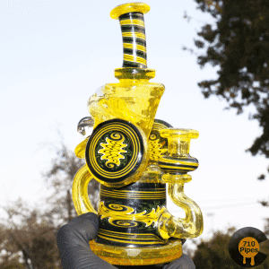 Hedman yellow and black glass recycler bong outdoors