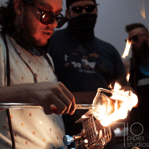 Glass artist using a torch flame to shape a glass piece at 710 Pipes Studios
