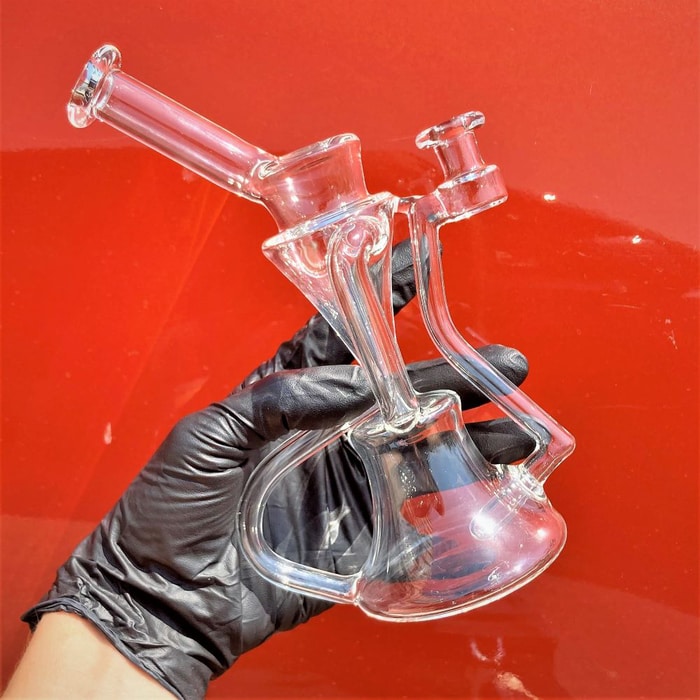 Heady glass recycler bong sold by 710 Pipes online smoke shop in gloved hand against red background