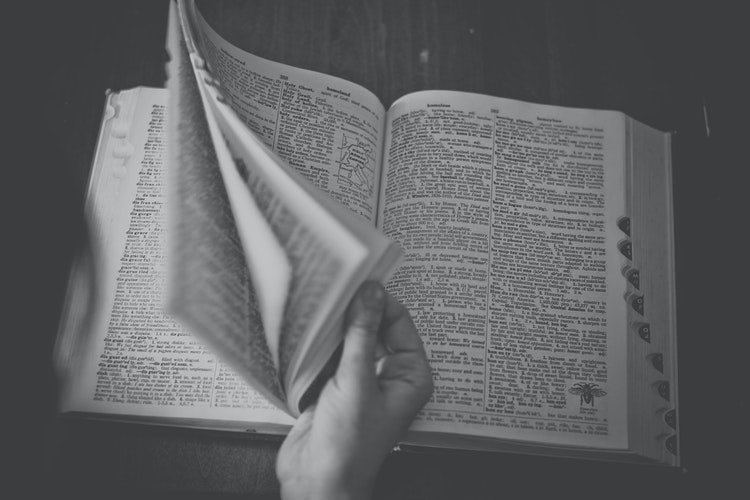 Person skimming "B" section of hardcover dictionary to learn new vocabulary