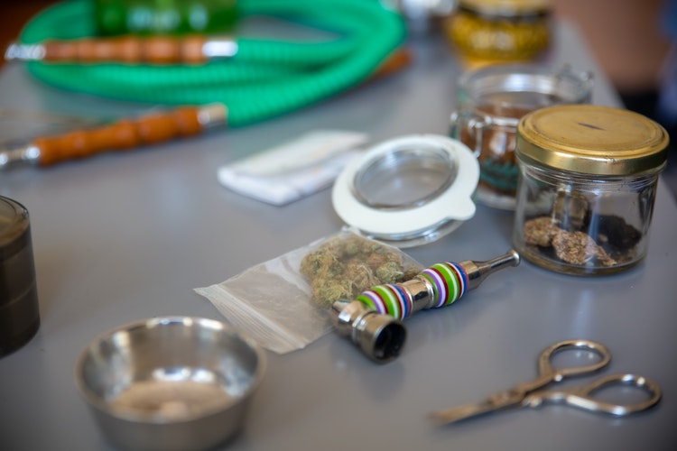 Cannabis nuggets, hand pipe and smoking accessories on table