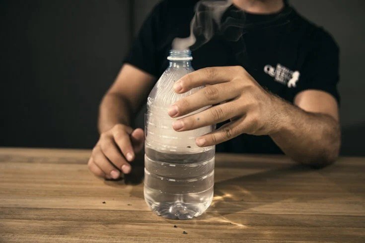 Gravity bong made from water bottle filled with smoke mid-use