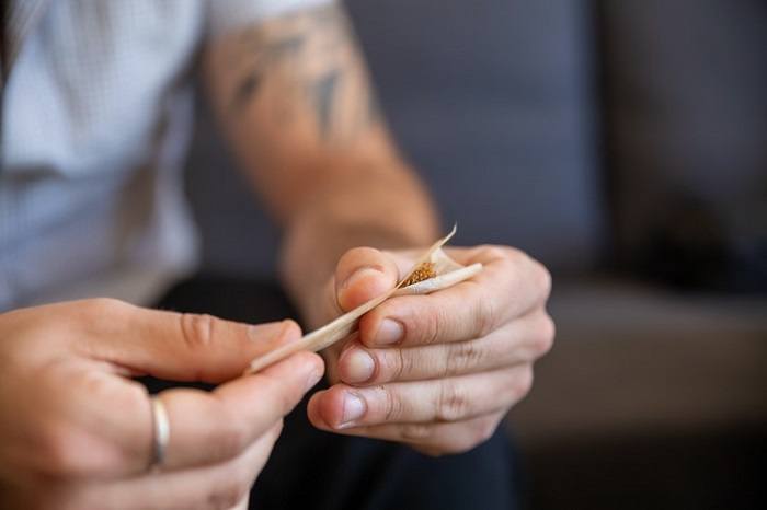 Man rolling joint using hemp rolling paper