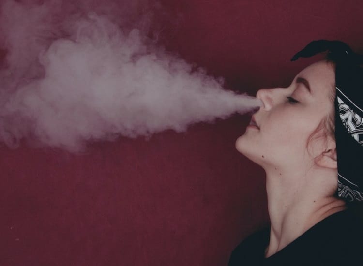 Woman exhaling vape cloud through nose