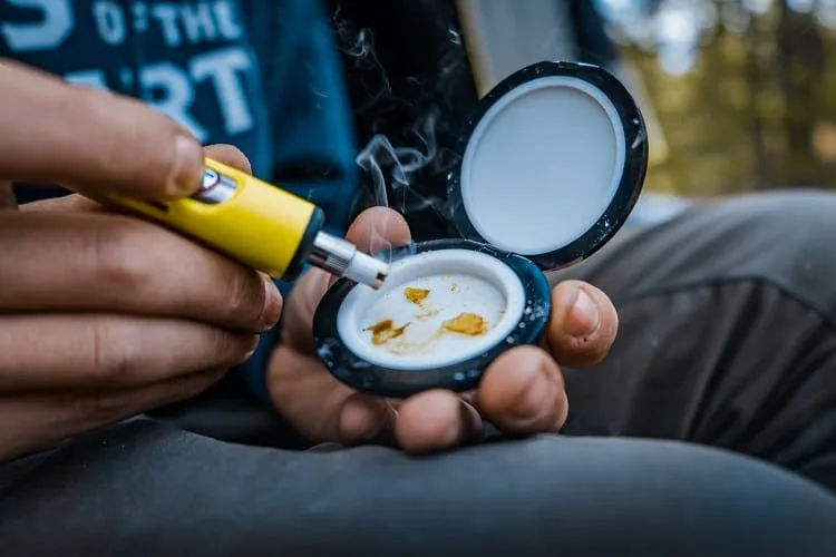 Yellow electronic nail dabbing wax shatter in circular storage container