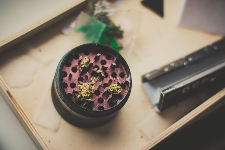 Black and maroon aluminum cannabis grinder beside rolling papers
