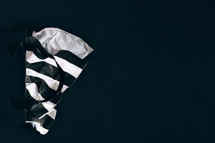 Sideways black gift bag with black-and-white striped tissue paper