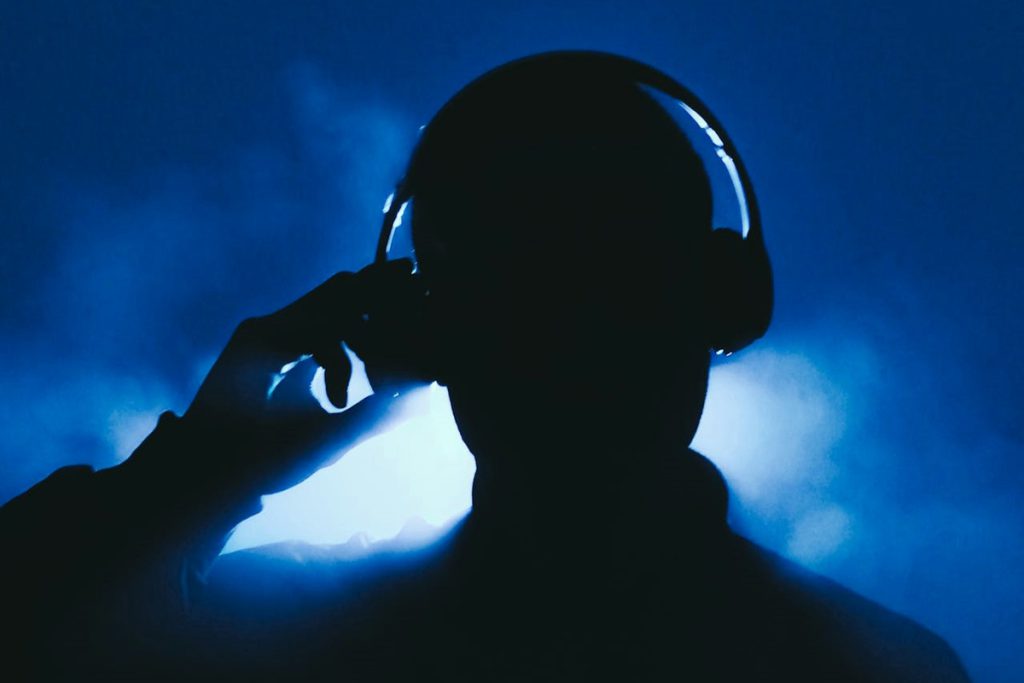 Silhouette of man wearing large headphones in dark, smoky room