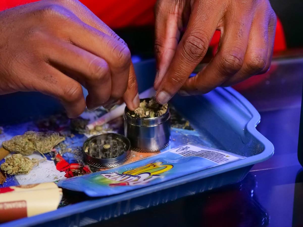 Grinding cannabis in aluminum grinder on multicolored rolling tray