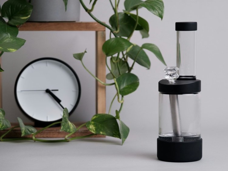 Clear bong beside analog clock and ficus plant