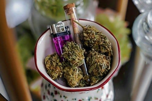 Close-up of cannabis buds in a bowl next to a lighter