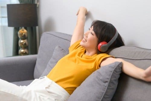Woman relaxing on a couch listening to music with headphones