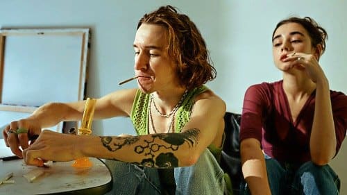 Two friends rolling and smoking together at a table