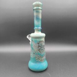 Illuminati 9-inch dab rig in fumed blue, teal glass rig with an etched dragon design